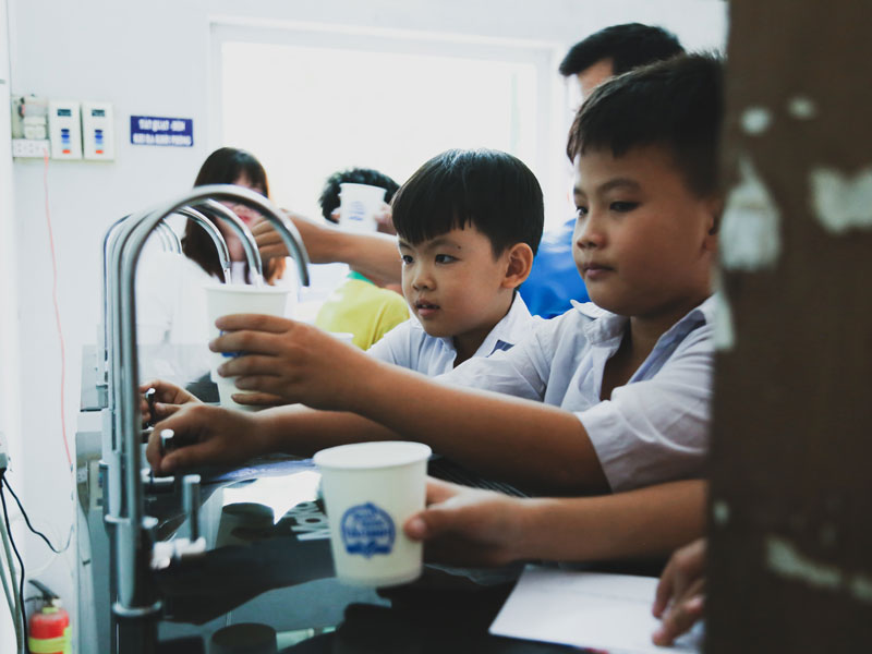 các em học sinh tiểu học cùng nhau lấy nước uống được lọc từ máy lọc nước daikiosan, makano